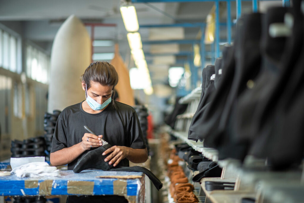 Operator hand-finishing black leather boots on the Foot On Shoes production line