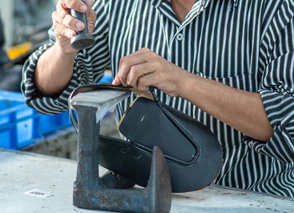 Craftsman hand-finishing a leather boot upper on a last
